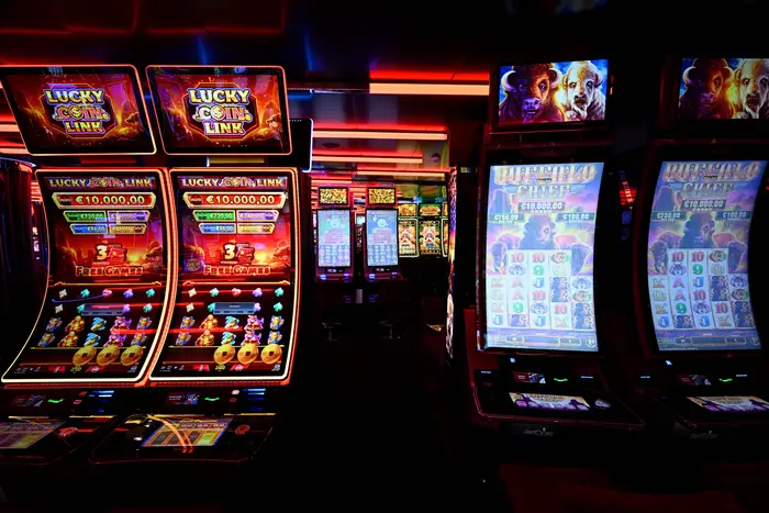 Colorful slot machines illuminate a casino floor.